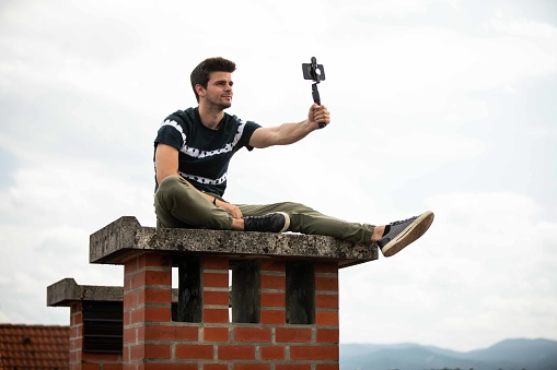 Man taking a selfie with a selfie stick and a phone.