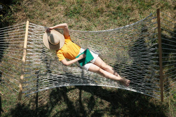 Young woman resting in hammock outdoors on sunny day, above view Young woman resting in hammock outdoors on sunny day, above view hammock relaxation women front or back yard stock pictures, royalty-free photos & images