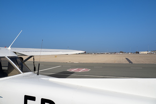 Light aircraft on a spacious airport apron. White wings against a blue sky. Empty airfield as a flight school concept.
