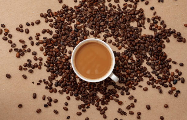 istock Cup of coffee with coffee beans on paper background. Top view 1402848065