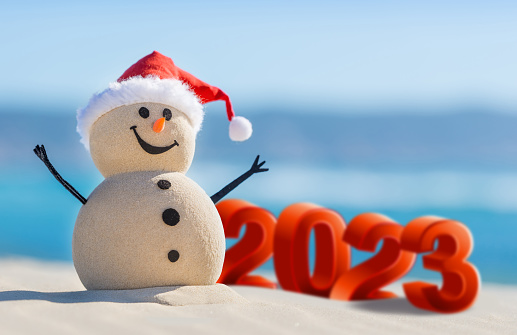 Two Sandy Snowmen are celebrating a New Year on a beautiful beach with 2023 3d text, concept for new year 2023