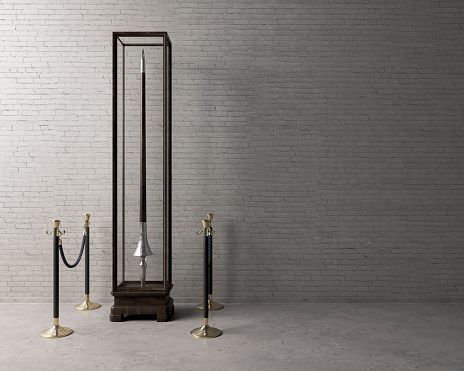 A concept showing an upright medieval lance on display in a wood and glass display cabinet surrounded by barrier rope in a light museum setting  - 3D render