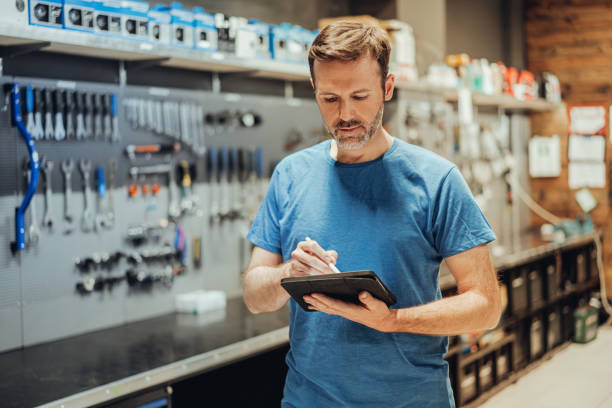 istock male bicycle mechanic checking with tablet a bicycle in his workshop 1402849909