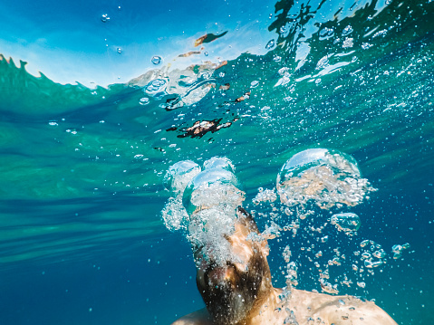 Bearded man making air bubbles underwater for fun, taken with waterproof wearable camera