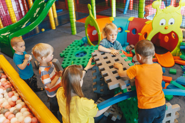 istock Educational group activity at the kindergarten. Happy children playing with foam blocks with young teacher babysitter 1402850379