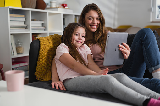 mother and daughter relaxing at home and using digital tablet