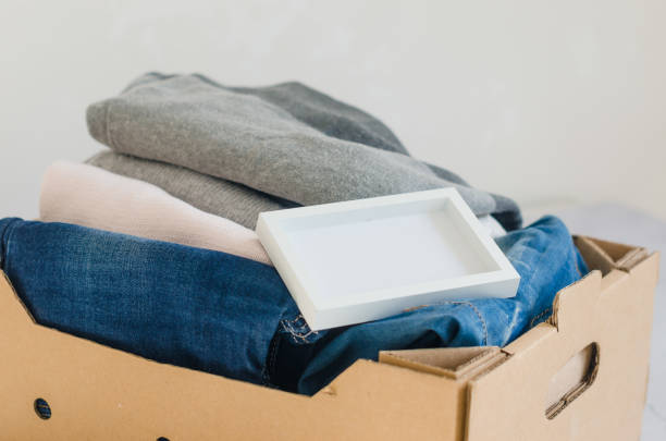 istock Cardbox with clothes, sweaters  and  blue jeans on grey background 1402852956