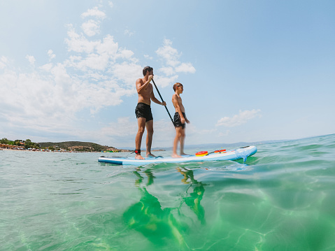 Photo of man and his son paddleboarding together.