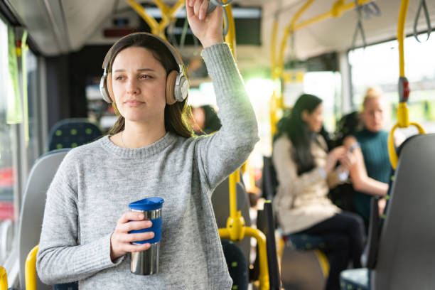 버스에 서서 커피를 들고 있는 여자 윙윙 헤드폰 - public transportation audio 뉴스 사진 이미지