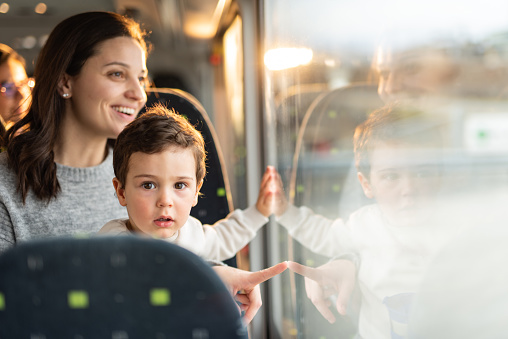 Happy mother and son on a bus looking out of the window