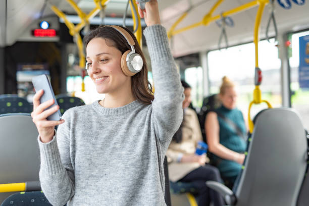 Woman listening music on phone in bus stock photo
