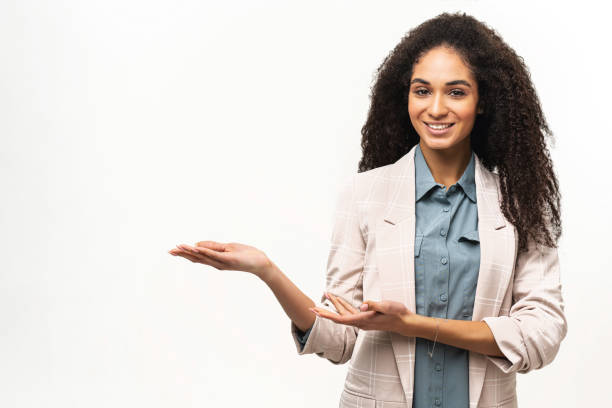 istock Charming multiracial woman with Afro hairstyle indicating palms at empty space isolated on white background, smiling female student advertising 1402857316