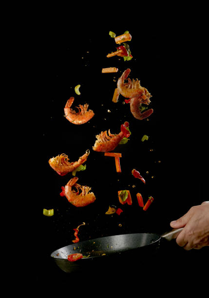 istock Crop chef roasting shrimps and veggies in frying pan 1402858146
