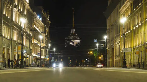 Busy road on background of ancient architecture and tower at night. Action. Timelapse of busy night street with ancient architecture. Luminous Nevsky avenue in Saint Petersburg at night.