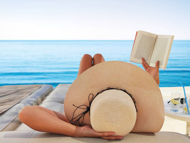 istock Young woman reads a book on the beach 1402860687