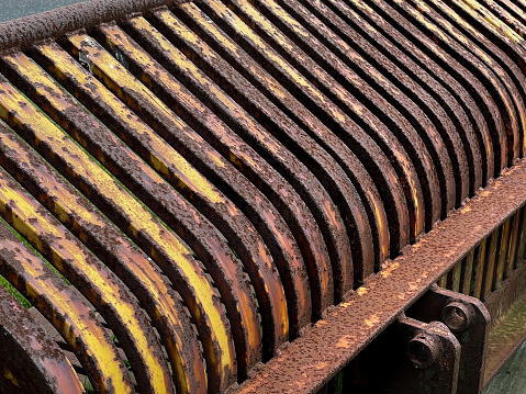 close up of a rusty, old, skeleton bucket used on farms to separate rocks and debris from soil while attached to a tractor, on sale at a salvage yard, Long Island, New York