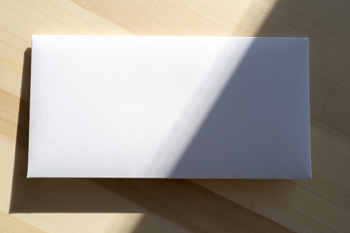 Blank white paper sheet, postcard, envelope as mockup and sunny light on surface