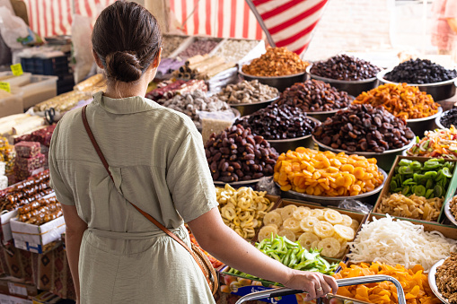 A woman at the street actual market chooses fresh organic fruits and vegetables