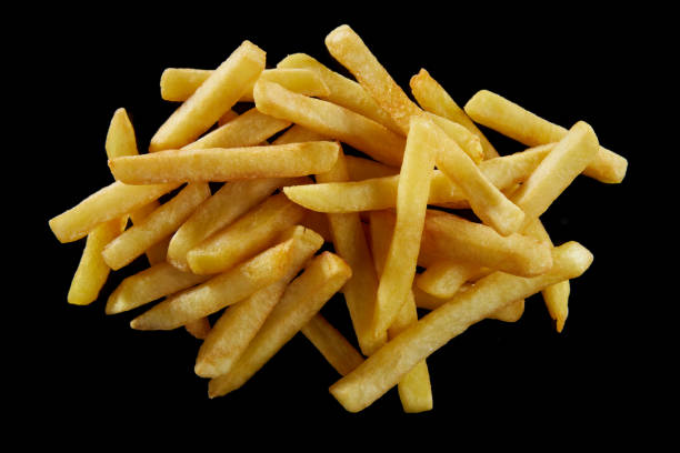 Crispy French fries on black background From above of heap of delicious crunchy French fries stacked on black background fried potato stock pictures, royalty-free photos & images