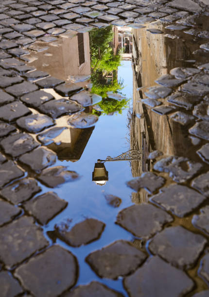 lampadaire réfléchi dans une flaque d’eau, rome italie - puddle rome reflection street photos et images de collection