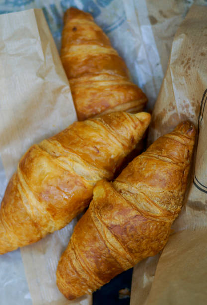 istock Three freshly baked croissants on a paper bag top view 1402862345