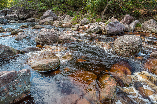 Detail of rocky river bed, with sedimentary rocks and reddish water in Chapada Diamantina, Bahia, Brazil