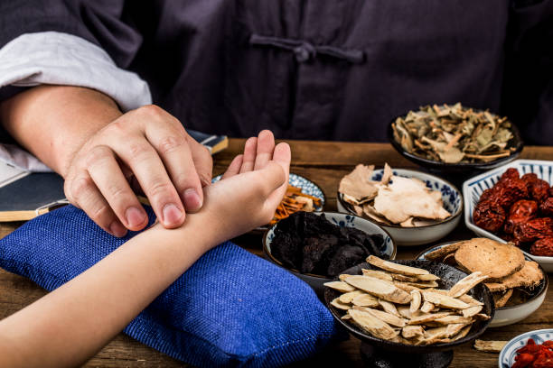 el viejo doctor de la medicina tradicional china al pulso del paciente - medicina herbaria fotografías e imágenes de stock