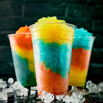 Colorful glasses of Slush summer drink in a row as a close up.
