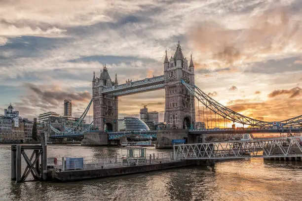 Photo of Tower Bridge against colorful sunset with pier in London, England, UK