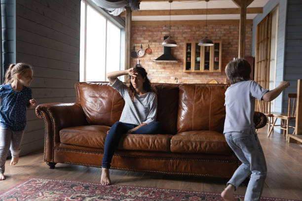 istock Stressed young mother feeling exhausted of hyperactive small children. 1402867212