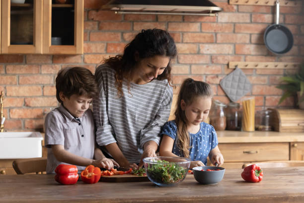 istock Smiling young mother teaching small children cooking. 1402867226