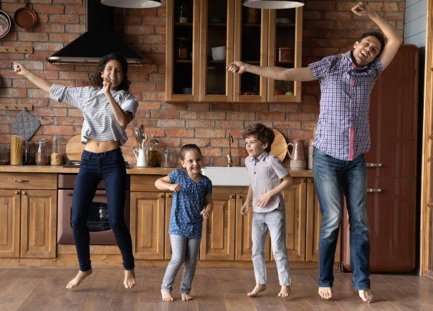 istock Happy young parents jumping with cute children in kitchen. 1402867229