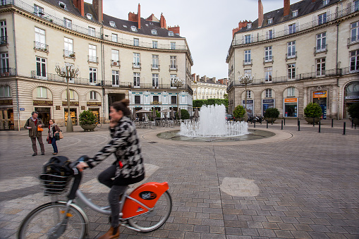 05-09-2016  Nantes  France. Downtown of Nantes -  blurred woman on bicycle and  building and  fountain Graslin