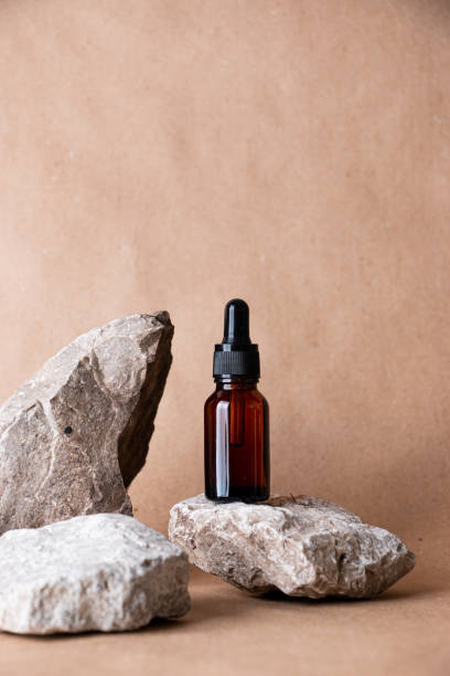 istock Glass bottles on stones on a pastel background. Cosmetic container mockup with place for text. The concept of natural cosmetics for skin care. 1402872908