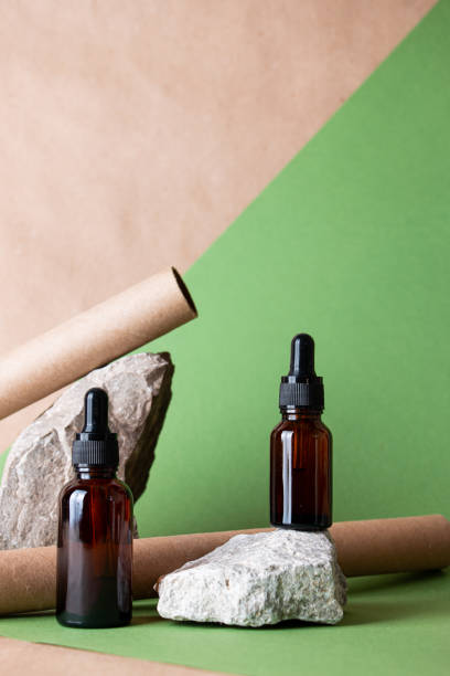 istock Glass bottles on stones on a pastel background. Cosmetic container mockup with place for text. The concept of natural cosmetics for skin care. 1402872951