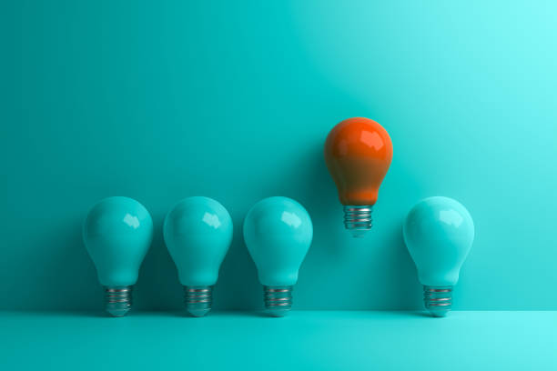 Orange lamp stands out from other lamps on a turquoise background. stock photo