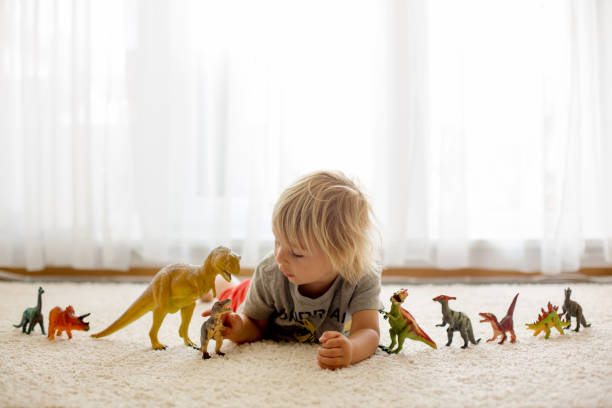 istock Blond toddler child, playing with dinosaurs at home 1402874376