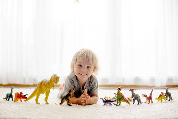 istock Blond toddler child, playing with dinosaurs at home 1402874391
