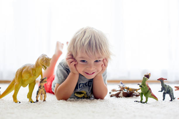 istock Blond toddler child, playing with dinosaurs at home 1402874402