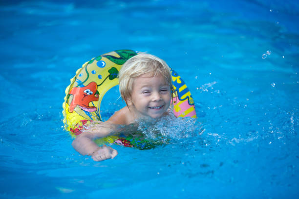 istock Cute toddler boy, swimming in pool with board 1402874417