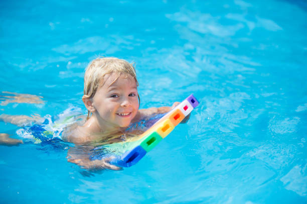 istock Cute toddler boy, swimming in pool with board 1402874434