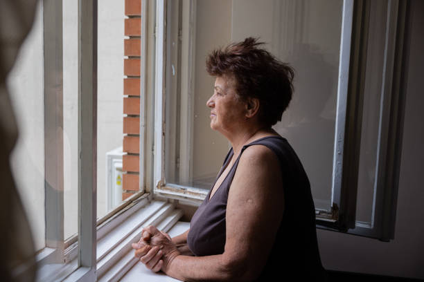 istock Curious but lonely Caucasian woman looking through window 1402874843