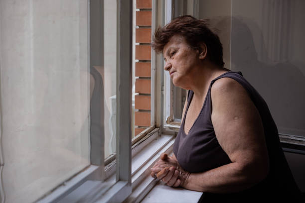 istock Curious but lonely Caucasian woman looking through window 1402875397