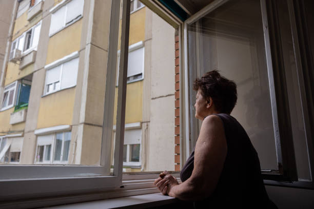istock Curious but lonely Caucasian woman looking through window 1402875399