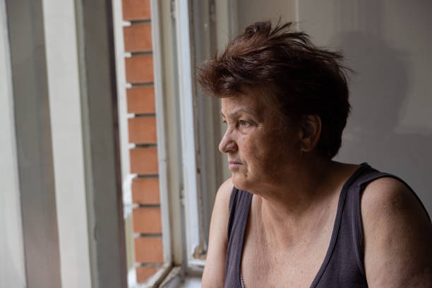 istock Curious but lonely Caucasian woman looking through window 1402875421