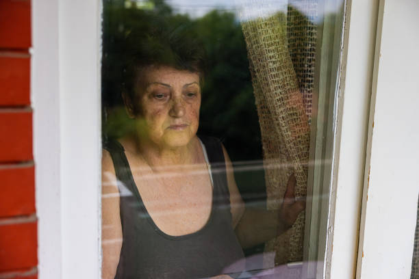 Senior woman alone on her house window