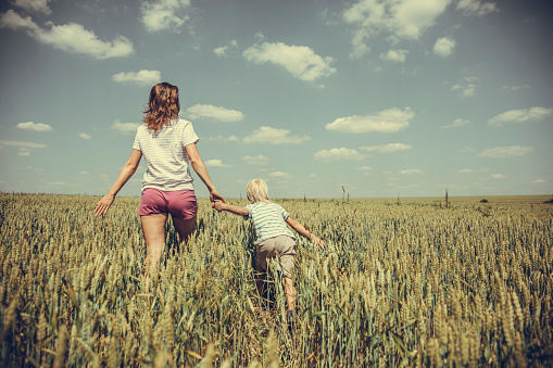 Mid adult woman and boy enjoyng freedom in the wheat field on a summer day
