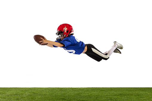 Flight. Athletic kid, beginner american football player in sports uniform and helmet training isolated on white background. Concept of sport, challenges, action, achievements.