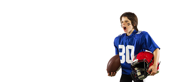 Winner emotions. Little boy, beginner american football player in sports uniform and helmet training isolated on white background. Concept of sport, challenges, action, achievements. Flyer for ad