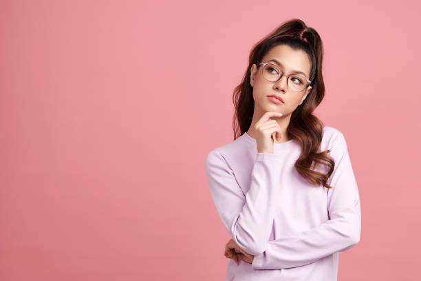 istock Curious Asian girl is thinking and standing on pink background with curious face, blank copy space for your advertising content. 1402878511